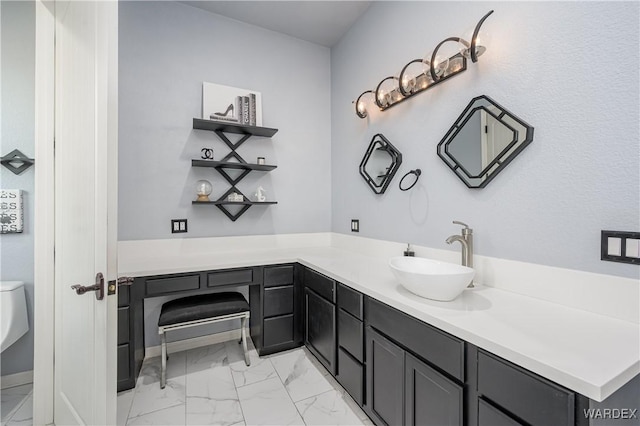 bathroom with toilet, marble finish floor, and vanity