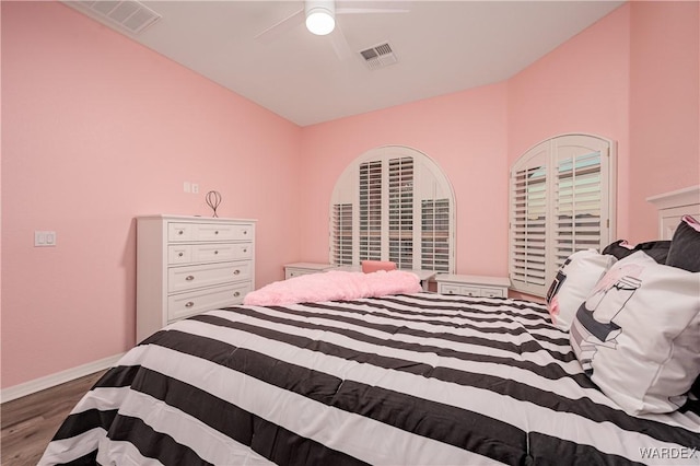 bedroom featuring a ceiling fan, baseboards, visible vents, and wood finished floors