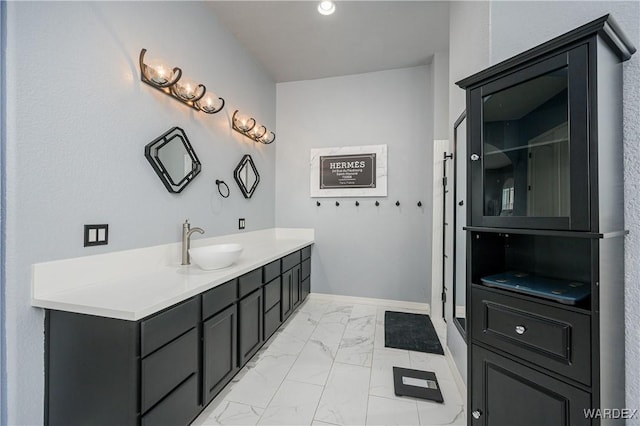 full bath with marble finish floor, vanity, and baseboards