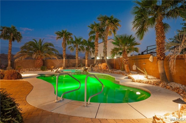 pool at dusk with a fenced in pool and a fenced backyard