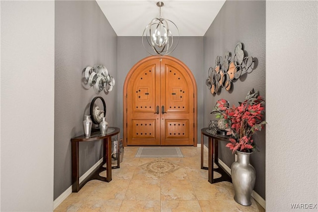 foyer entrance with baseboards and an inviting chandelier