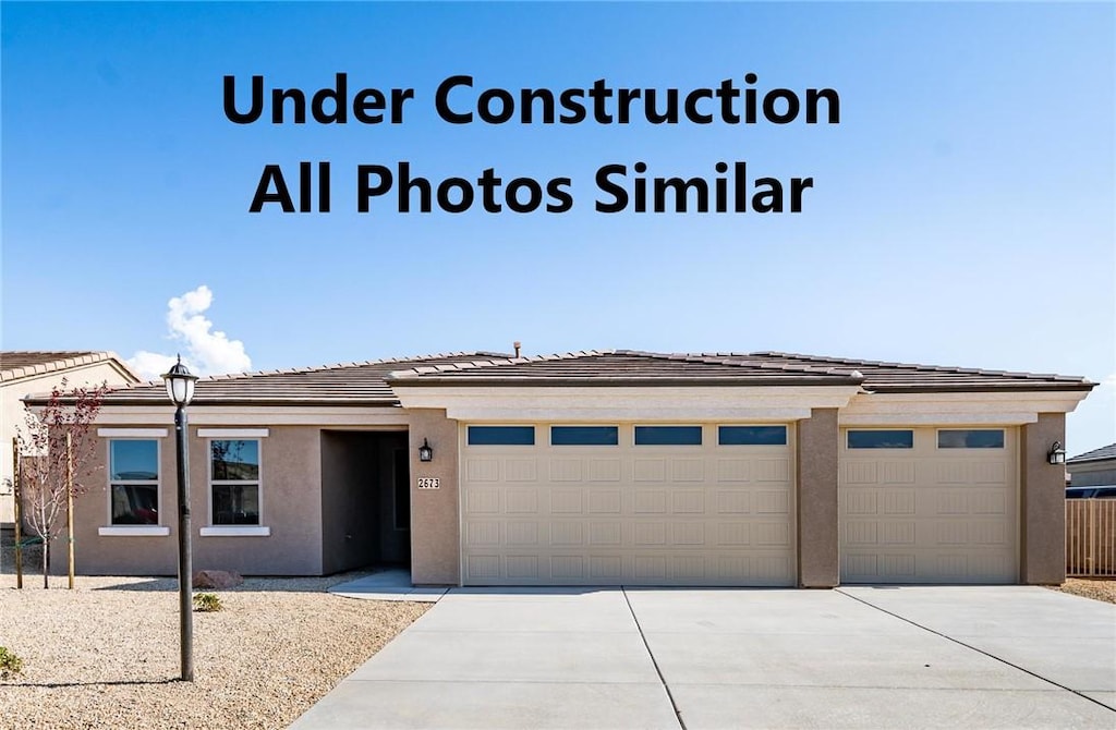 3536 Charleston Loop, Kingman, AZ 86401 - prairie-style house with driveway, stucco siding, a garage, and a tile roof