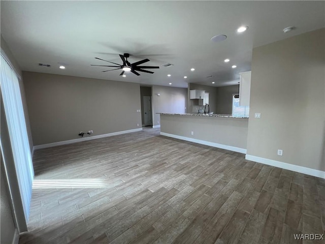 unfurnished living room featuring baseboards, recessed lighting, light wood-style flooring, and a ceiling fan