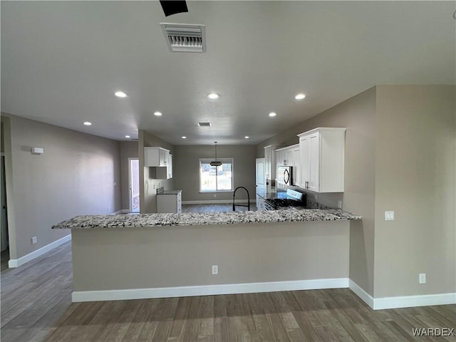 kitchen with visible vents, white cabinetry, stainless steel microwave, and a peninsula