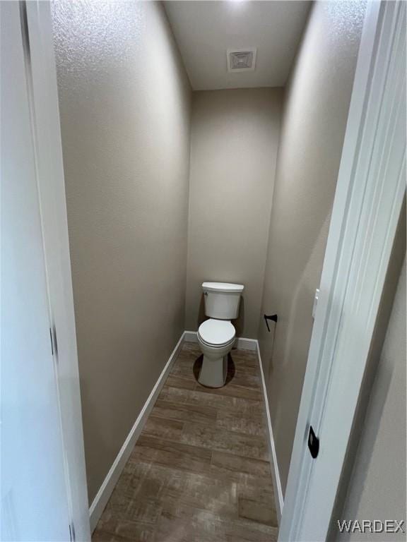 bathroom featuring toilet, baseboards, visible vents, and wood finished floors