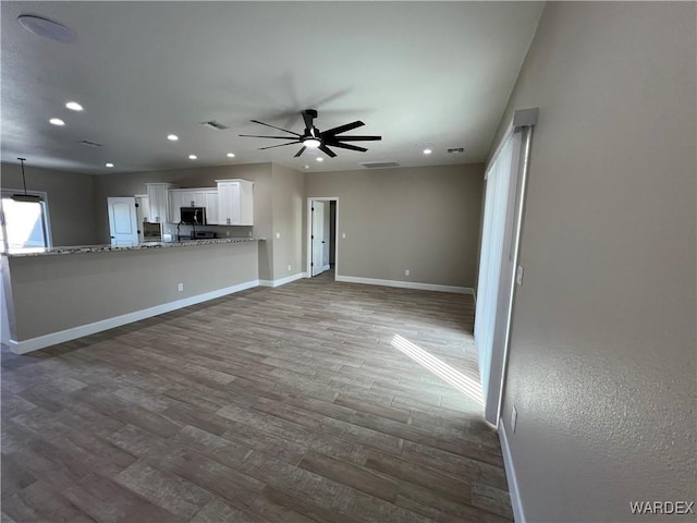 unfurnished living room featuring ceiling fan, recessed lighting, wood finished floors, visible vents, and baseboards