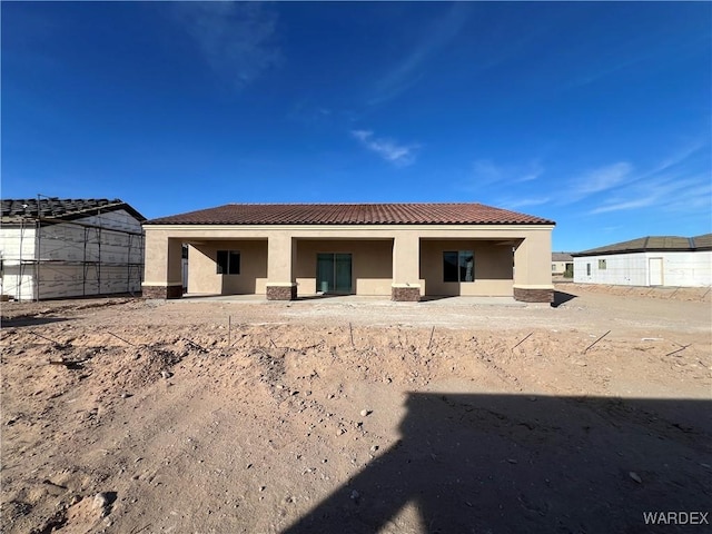 back of property featuring fence, a tiled roof, and stucco siding