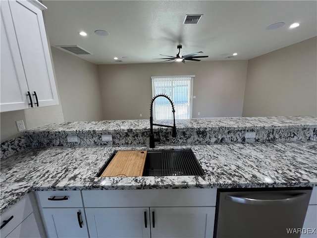 kitchen with light stone counters, white cabinets, a sink, and stainless steel dishwasher