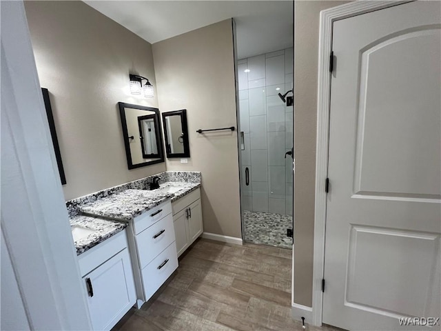 full bathroom with a shower stall, baseboards, wood finished floors, and vanity