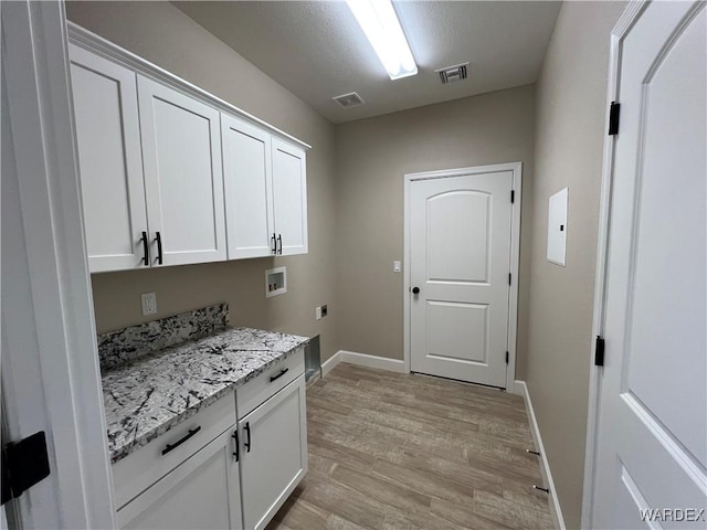 washroom with washer hookup, visible vents, cabinet space, light wood finished floors, and electric dryer hookup