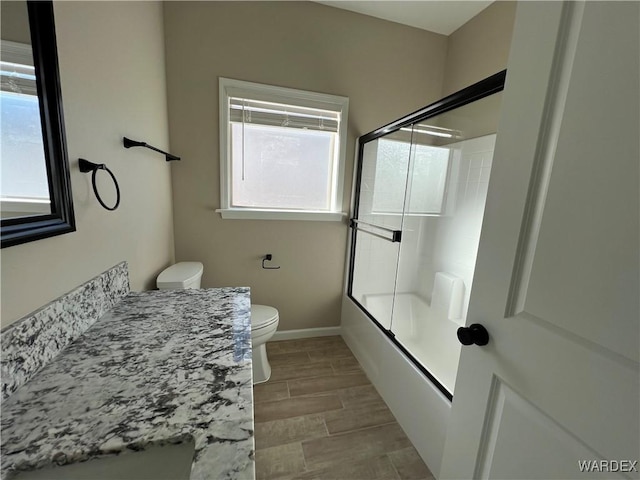 full bath featuring baseboards, toilet, shower / bath combination with glass door, vanity, and wood finish floors