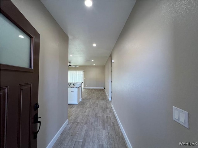 hall with recessed lighting, light wood-style flooring, and baseboards