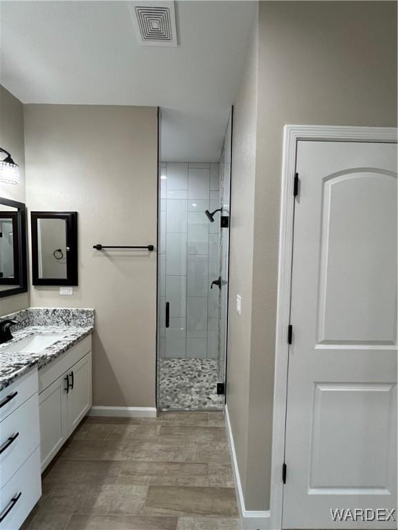 bathroom with visible vents, a stall shower, vanity, and baseboards