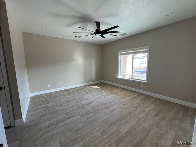 spare room featuring a ceiling fan, baseboards, and wood finished floors