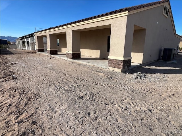 view of home's exterior with a patio, a tiled roof, cooling unit, a mountain view, and stucco siding