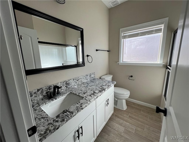 bathroom featuring wood finish floors, visible vents, toilet, vanity, and baseboards