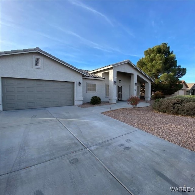 view of front of home with concrete driveway, an attached garage, a tile roof, and stucco siding