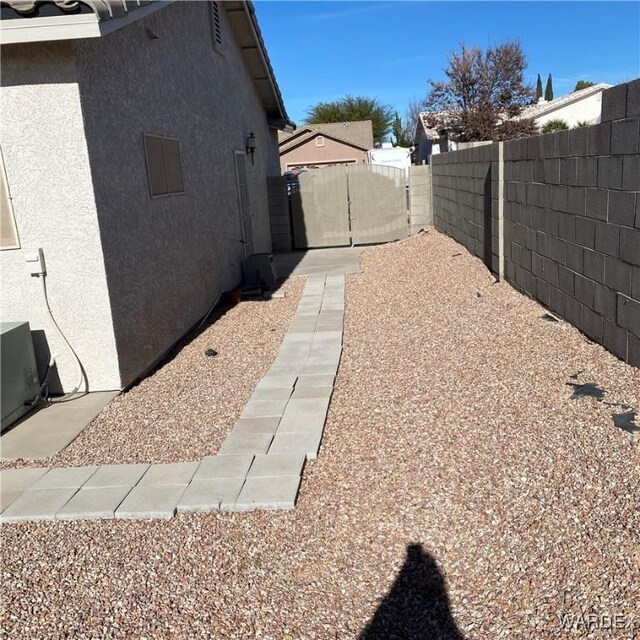 view of home's exterior with a fenced backyard, a gate, and stucco siding