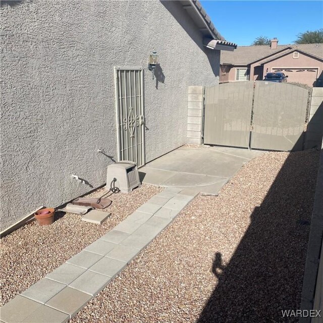 view of side of home featuring a gate, a tile roof, fence, and stucco siding