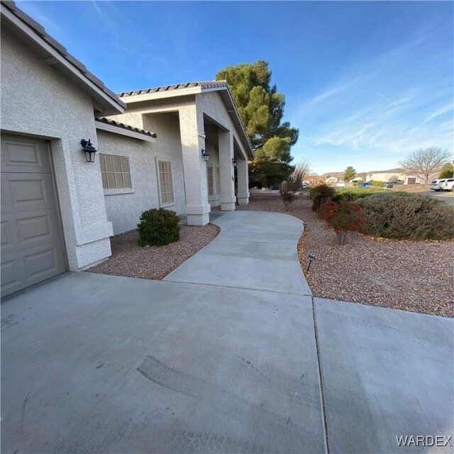 view of home's exterior featuring a garage, a tiled roof, and stucco siding