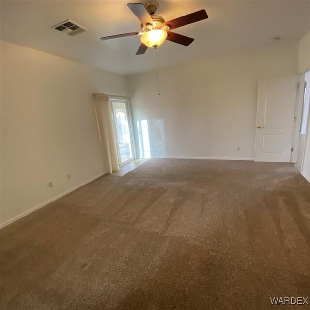 empty room with baseboards, visible vents, dark colored carpet, and a ceiling fan