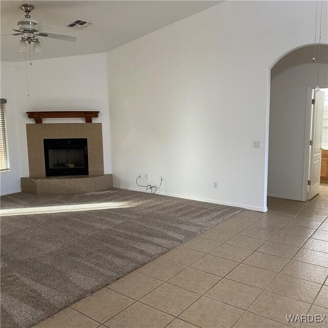 unfurnished living room featuring arched walkways, visible vents, ceiling fan, and light tile patterned flooring