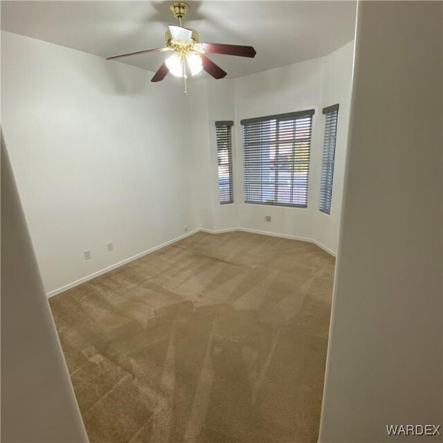 unfurnished room featuring carpet, baseboards, and a ceiling fan