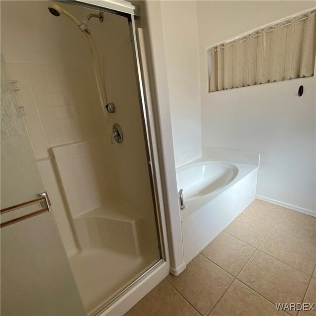 bathroom featuring a garden tub, a shower stall, baseboards, and tile patterned floors