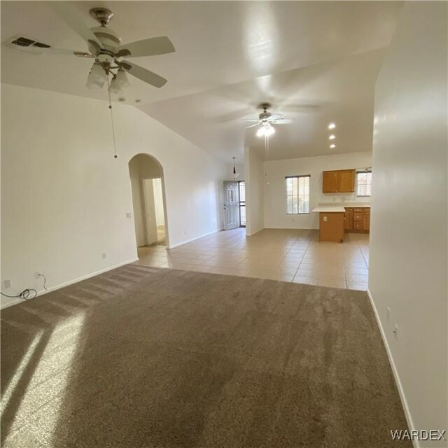 unfurnished living room with arched walkways, ceiling fan, light carpet, visible vents, and vaulted ceiling