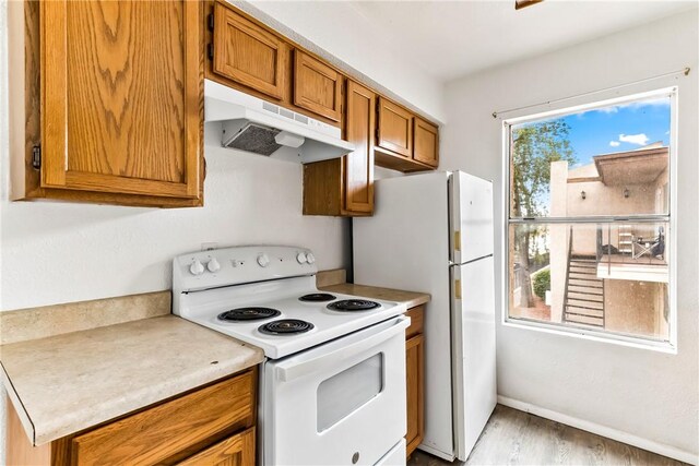 1280 Mohave Dr Unit 28, Bullhead City, AZ 86442 - kitchen with white appliances, under cabinet range hood, brown cabinetry, light wood-style floors, and light countertops