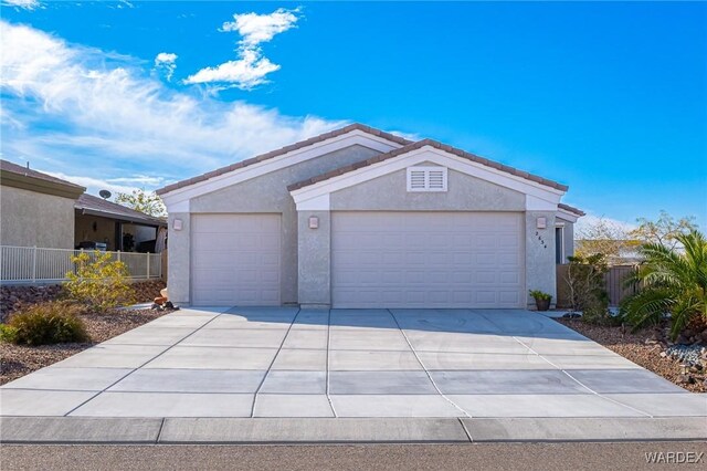 view of front facade featuring a garage, concrete driveway, fence, and stucco siding