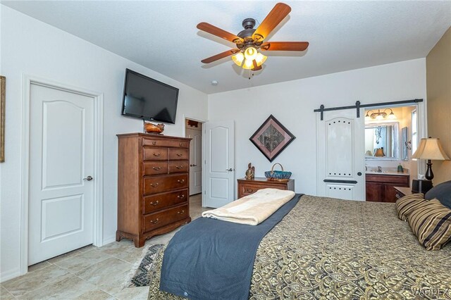 bedroom with ceiling fan and a barn door