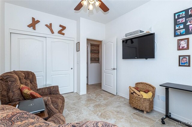 living area featuring ceiling fan and baseboards