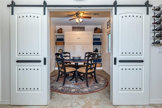 dining area featuring a barn door, visible vents, and ceiling fan