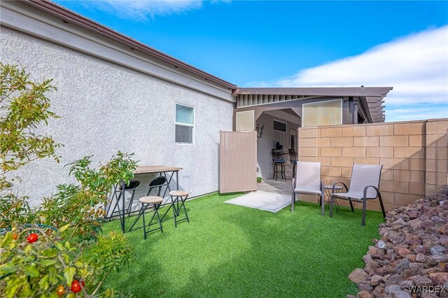 back of house with a yard, fence, and stucco siding