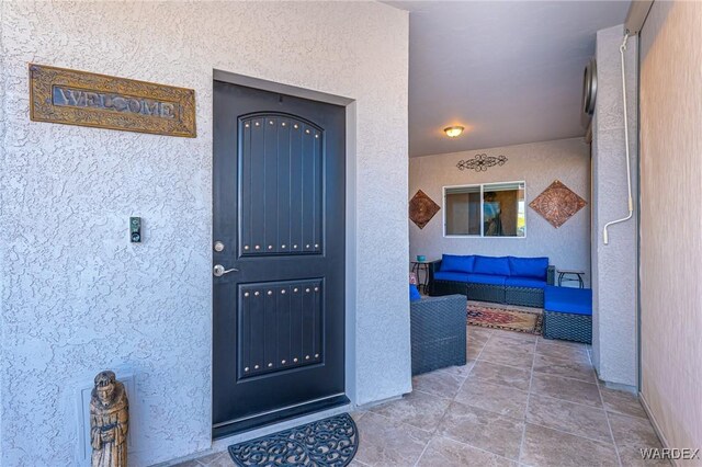 view of exterior entry featuring outdoor lounge area and stucco siding