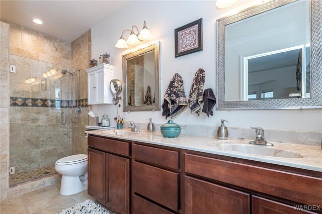 full bathroom with a sink, a shower stall, toilet, and double vanity