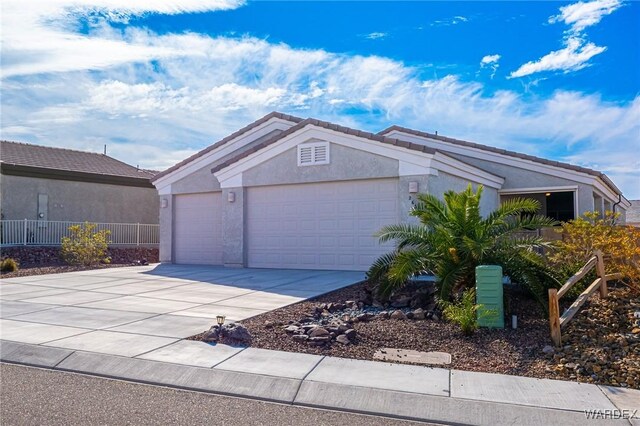 view of front of home featuring concrete driveway, a tile roof, an attached garage, fence, and stucco siding