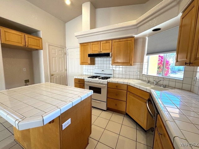 kitchen featuring a sink, backsplash, tile counters, dishwasher, and white gas range