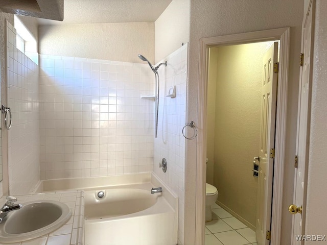 full bathroom with a textured wall, toilet, a sink, shower / washtub combination, and tile patterned floors