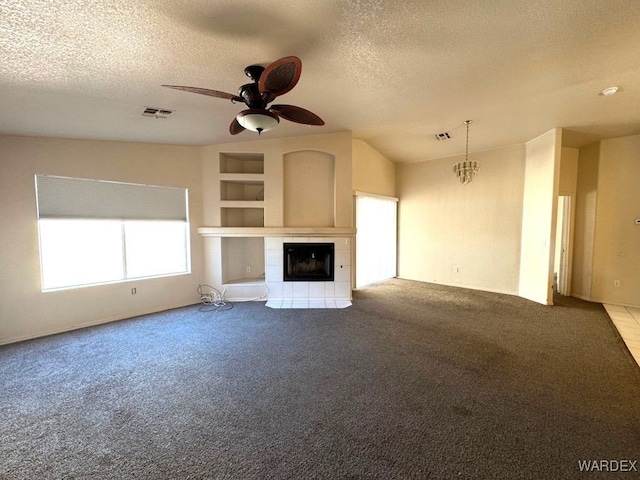 unfurnished living room featuring a textured ceiling, visible vents, built in features, a tiled fireplace, and carpet