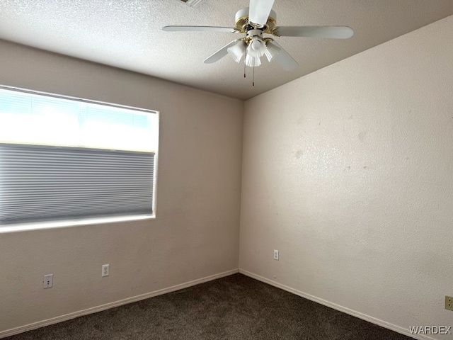 empty room with ceiling fan, baseboards, dark colored carpet, and a textured ceiling