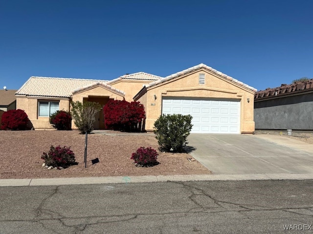 ranch-style house with an attached garage, a tiled roof, concrete driveway, and stucco siding