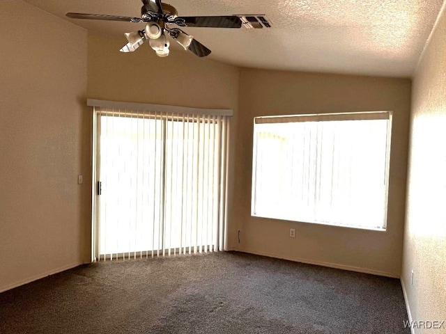 carpeted empty room featuring a ceiling fan, visible vents, vaulted ceiling, and a textured ceiling