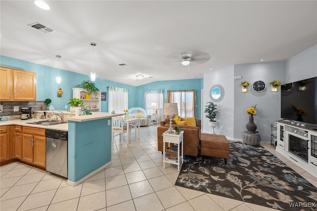 kitchen featuring light tile patterned floors, a sink, light countertops, stainless steel dishwasher, and hanging light fixtures