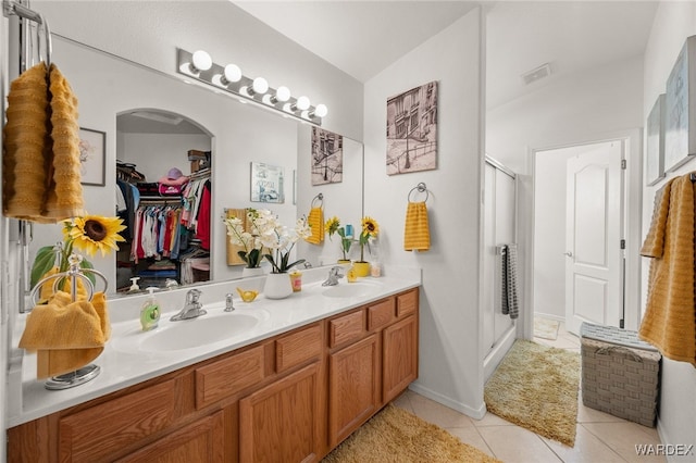 bathroom featuring a spacious closet, double vanity, a sink, and a shower stall