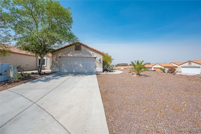 view of front facade with concrete driveway, an attached garage, a tile roof, and stucco siding