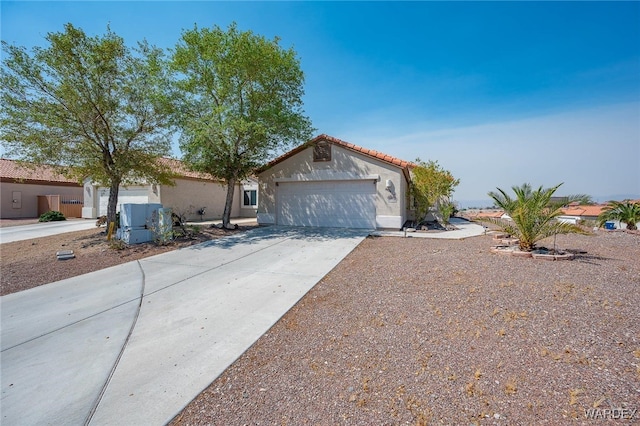 view of front of house featuring a garage, concrete driveway, a tile roof, and stucco siding