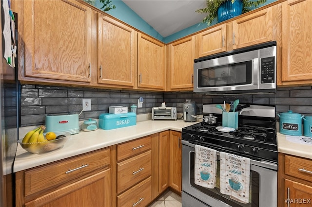 kitchen with light tile patterned floors, stainless steel appliances, backsplash, and light countertops