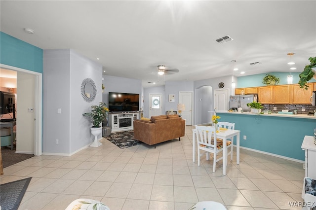 dining area with arched walkways, light tile patterned floors, visible vents, a ceiling fan, and baseboards